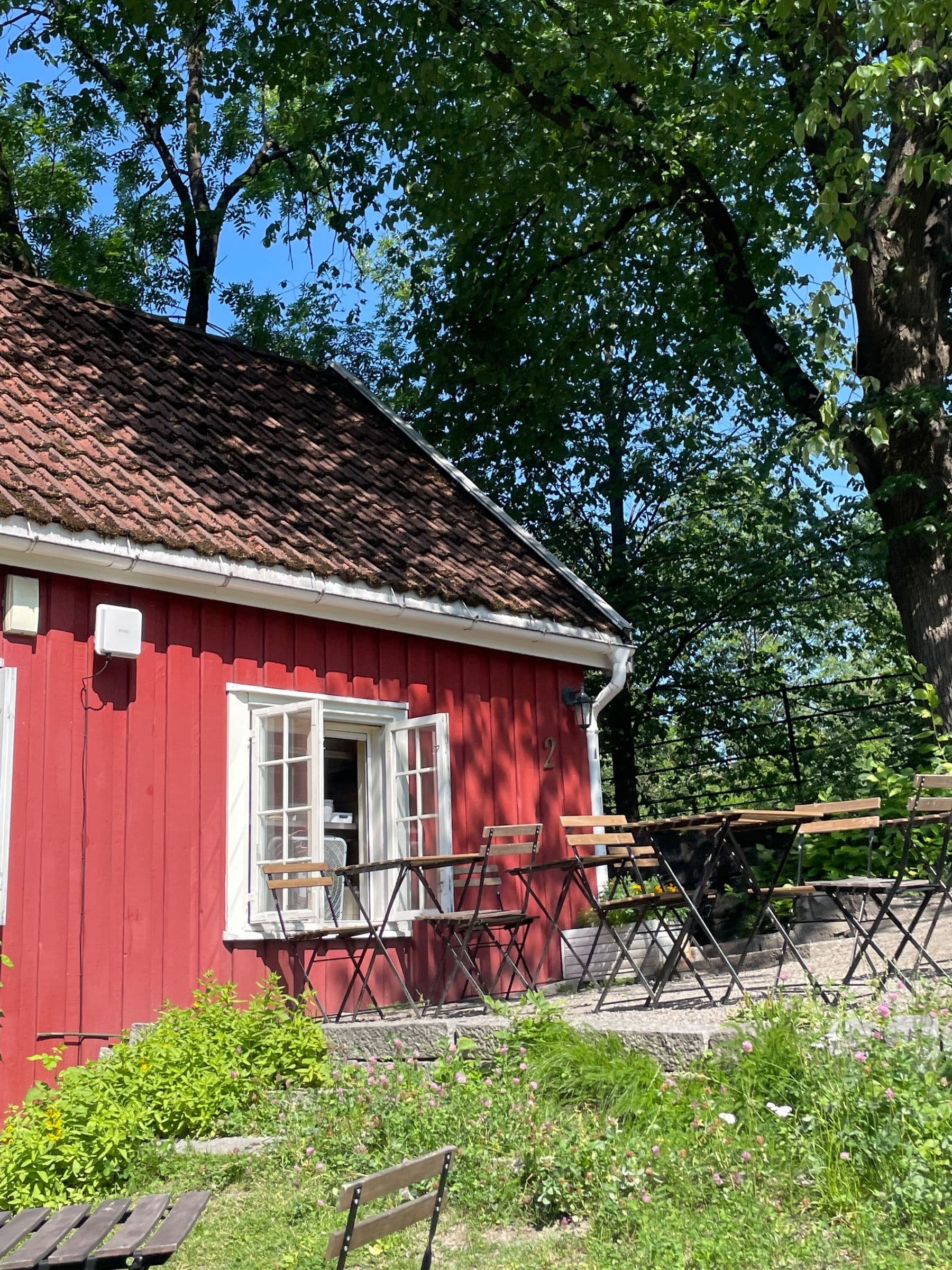The red timber cottage behind its white picket fence