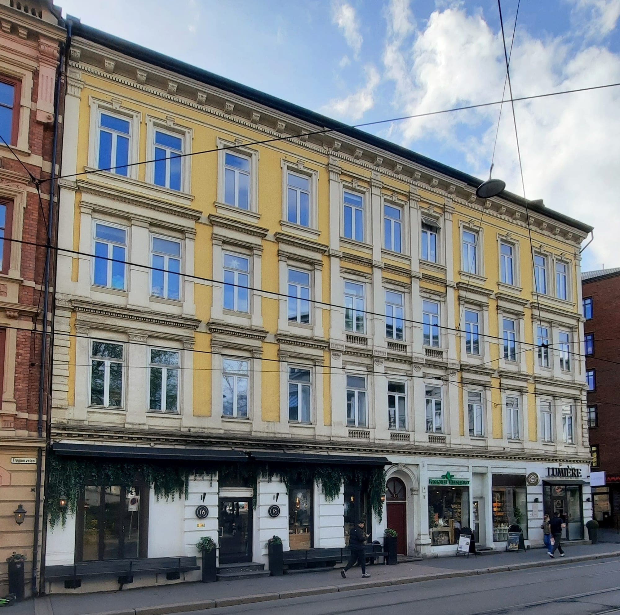 Street-level shopfronts under a yellow-and-white period façade