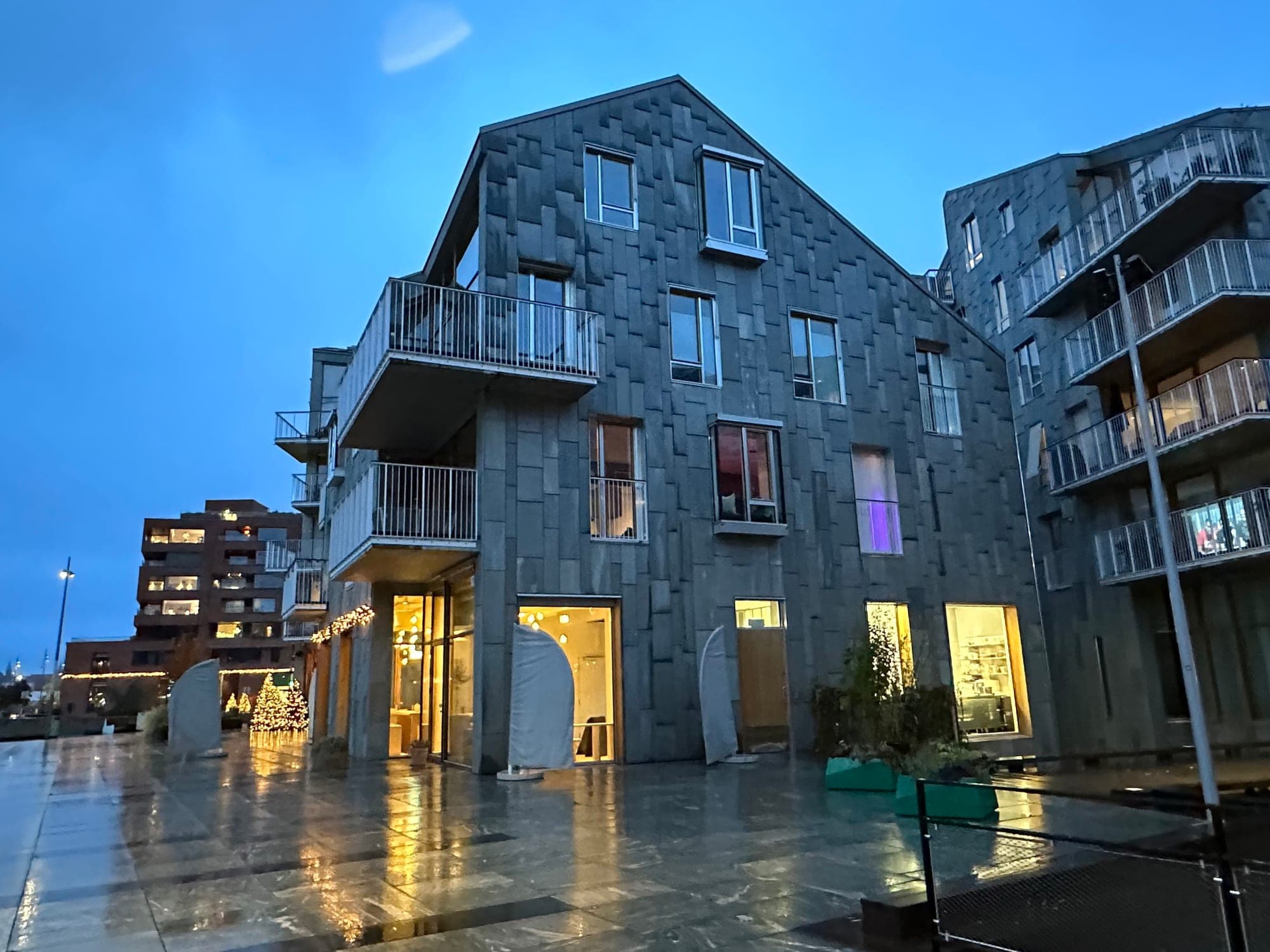 Kumi's warm-lit ground floor in a slate-clad Oslobukta block at dusk