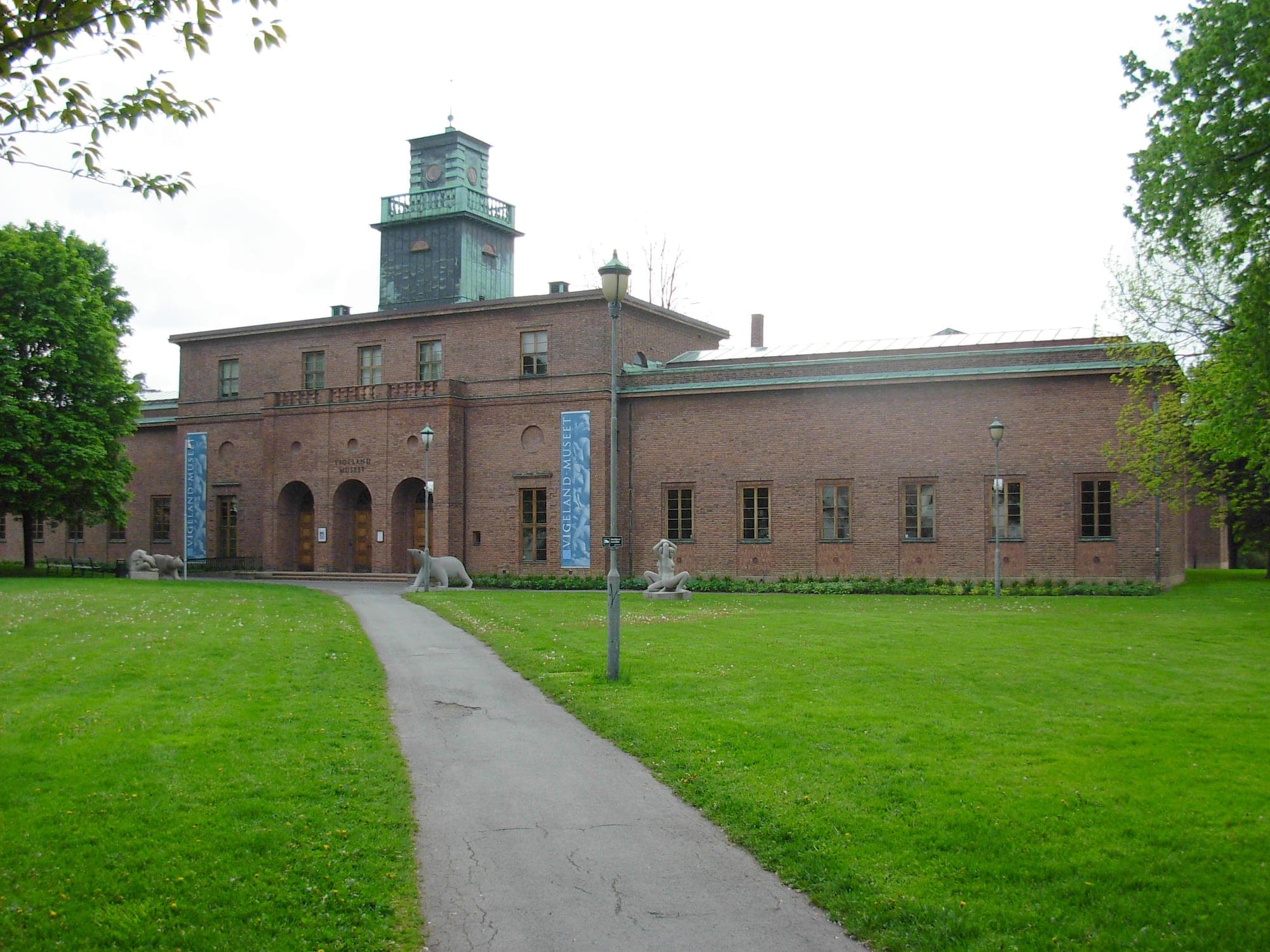 The Vigeland Museum in Frogner, Oslo — red-brick facade with its copper clock tower and sculptures on the lawn