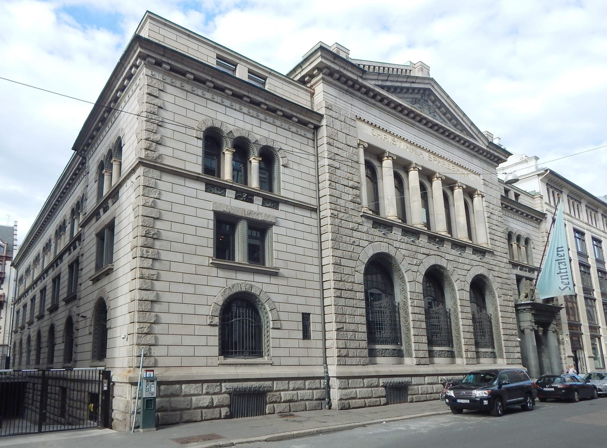 Monumental stone building with arched windows on a quiet street