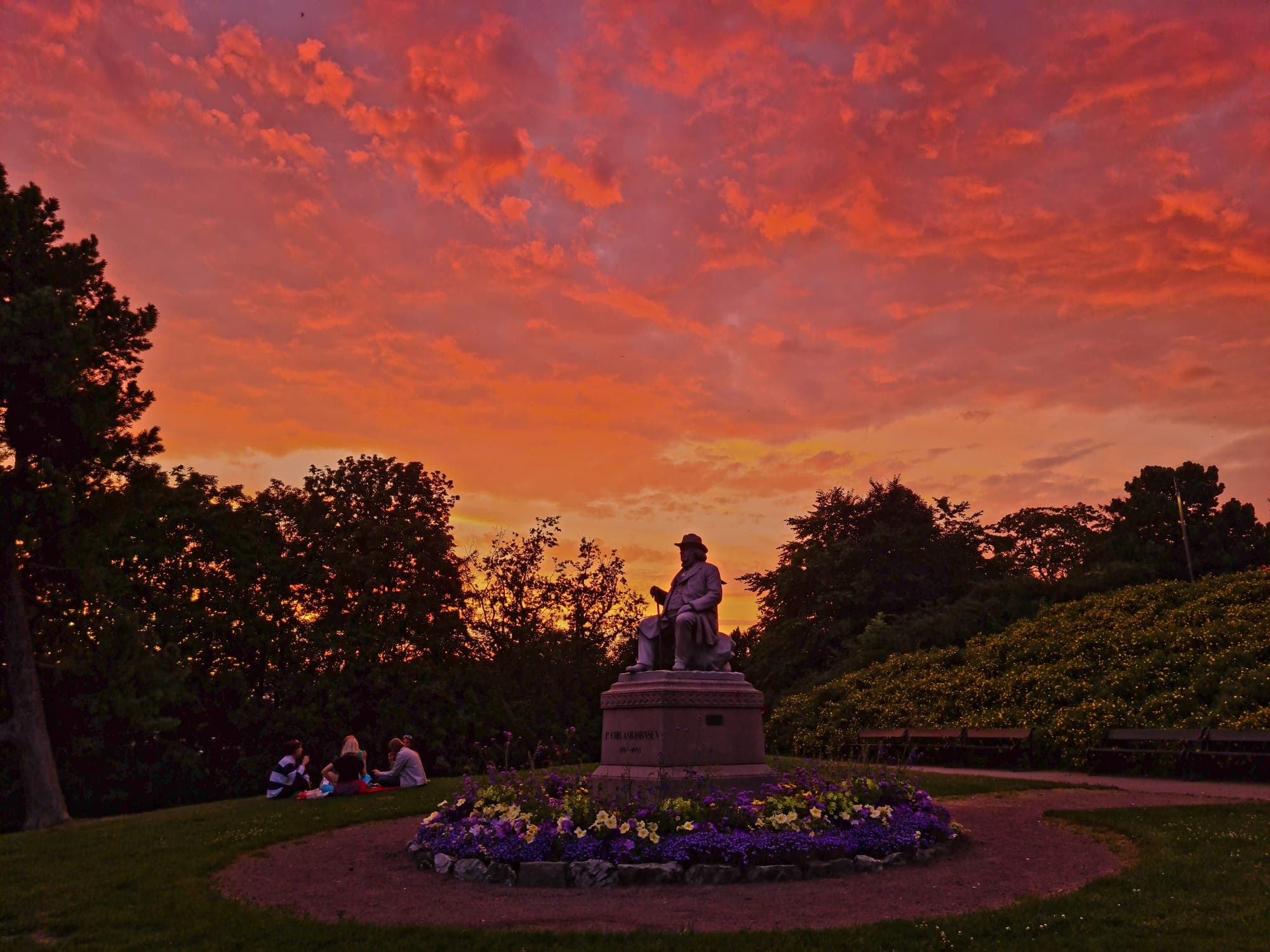 Fiery sunset sky over the statue and flowerbeds on the summit
