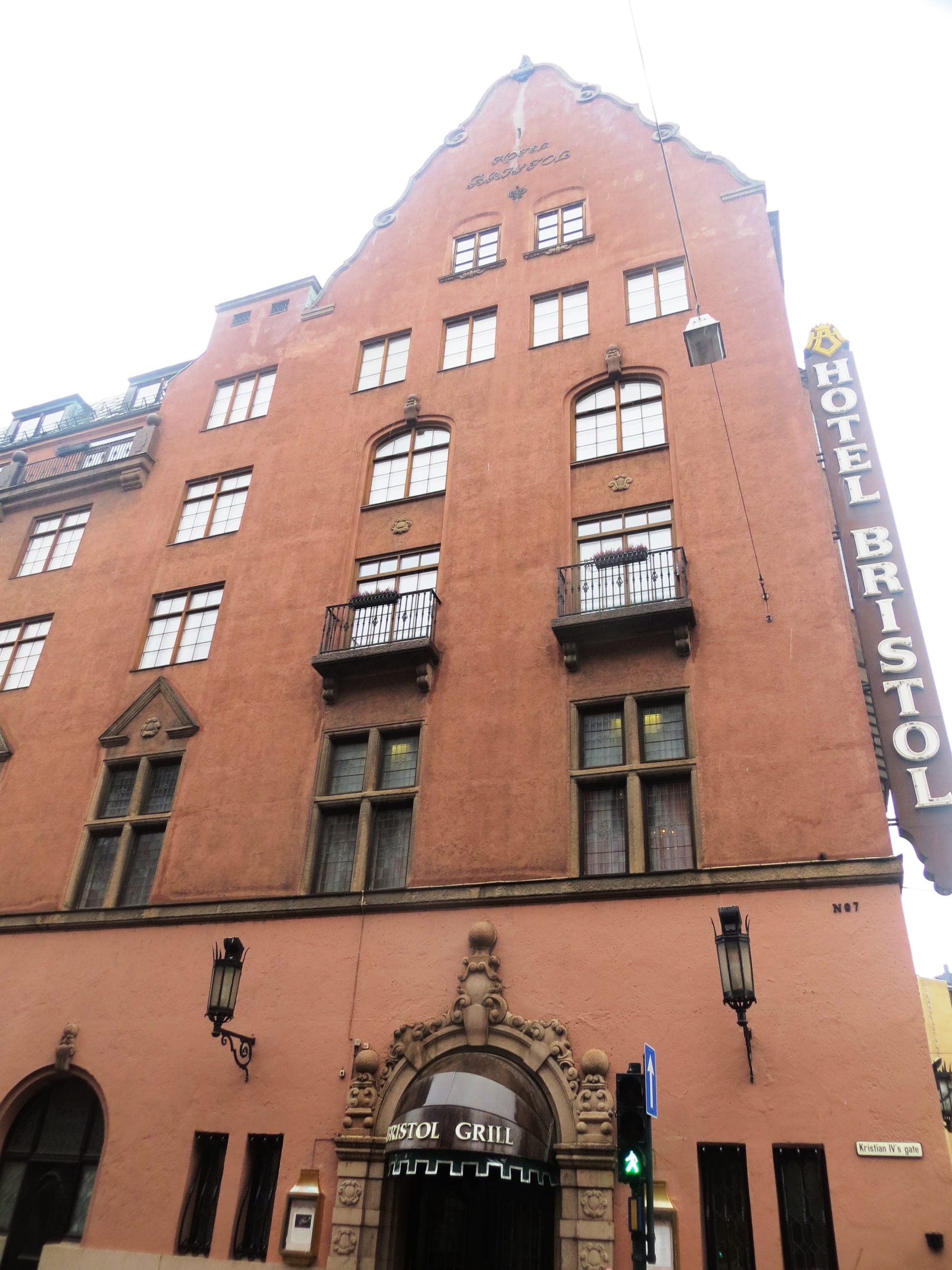 Hotel Bristol's red-brown façade and vertical hotel sign from below