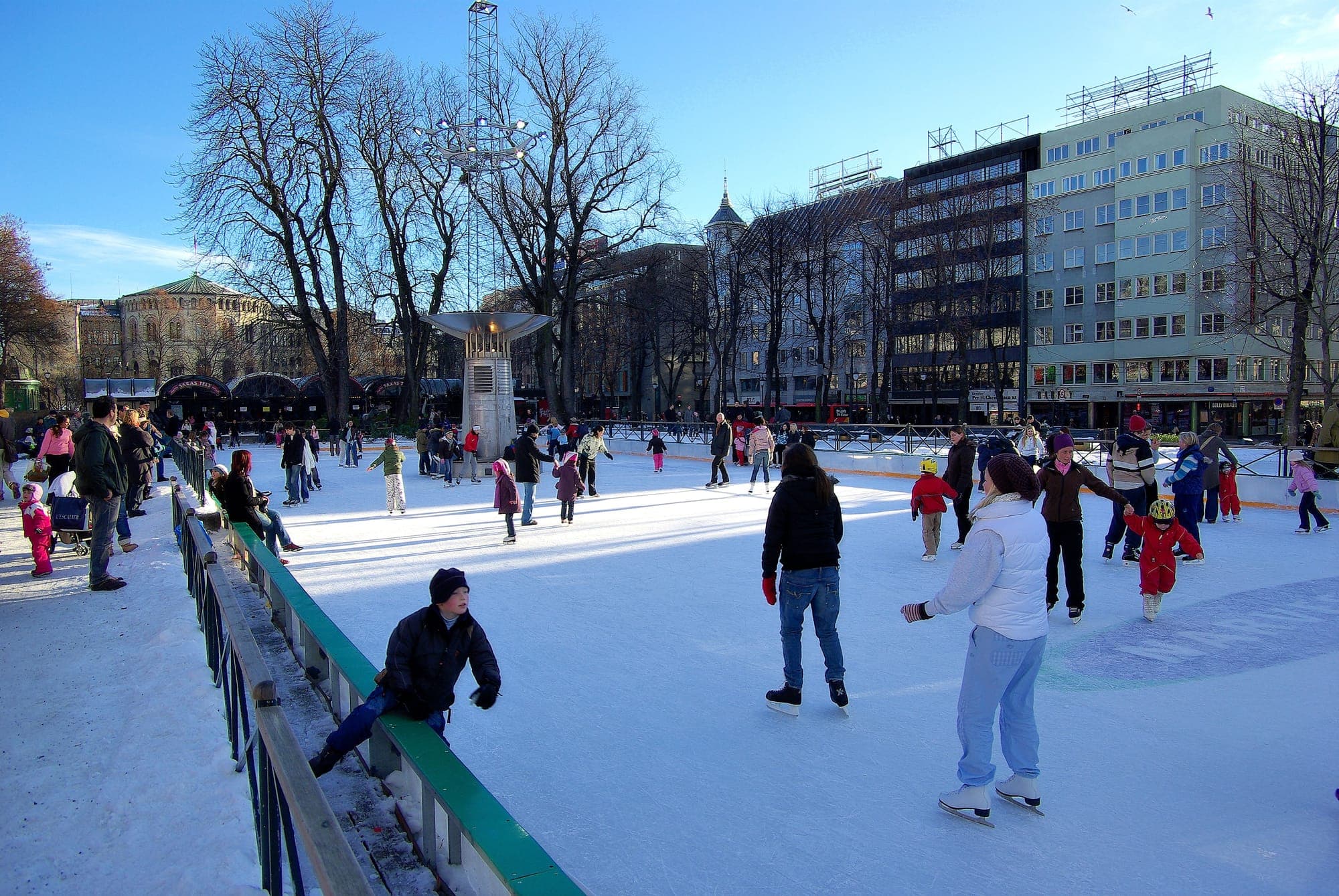 Crowds skating at Spikersuppa's rink between bare winter trees