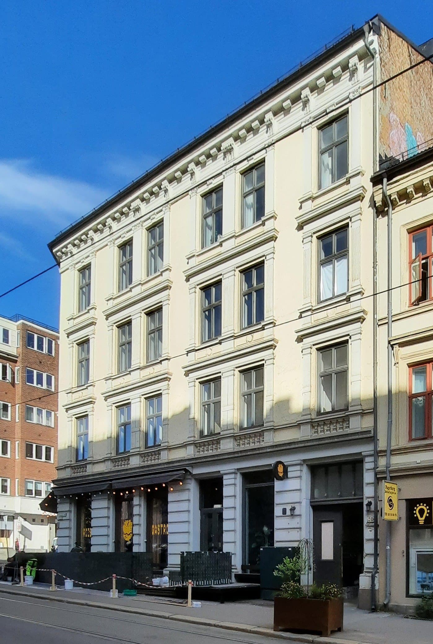 Sunlit pale-yellow period façade above Roze Gastro's corner