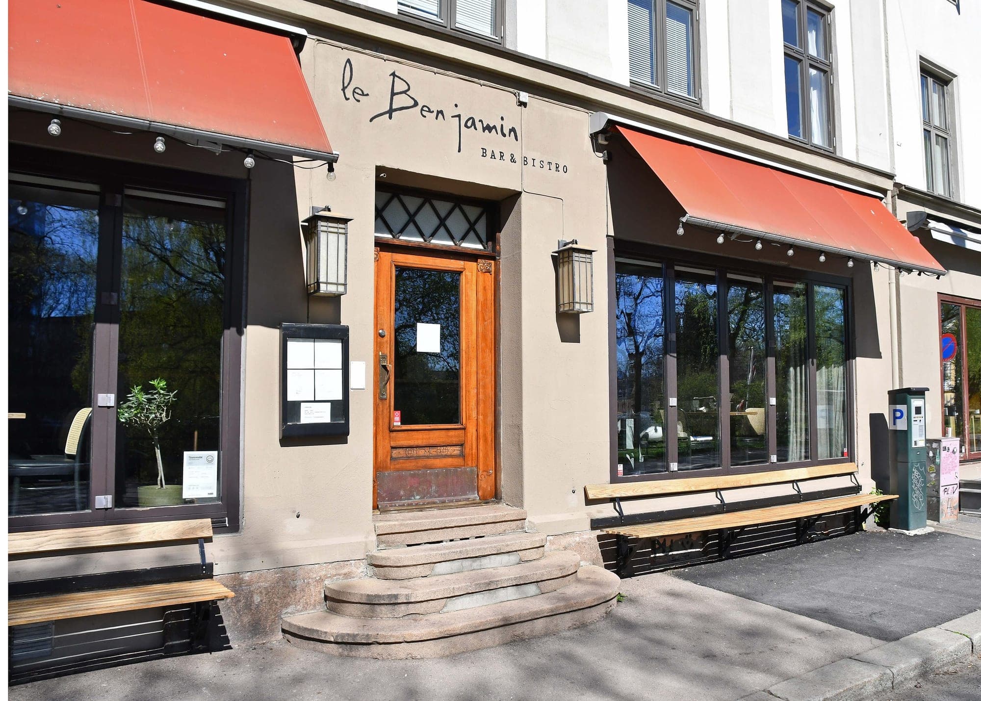 Le Benjamin's wooden door and red awnings above street benches