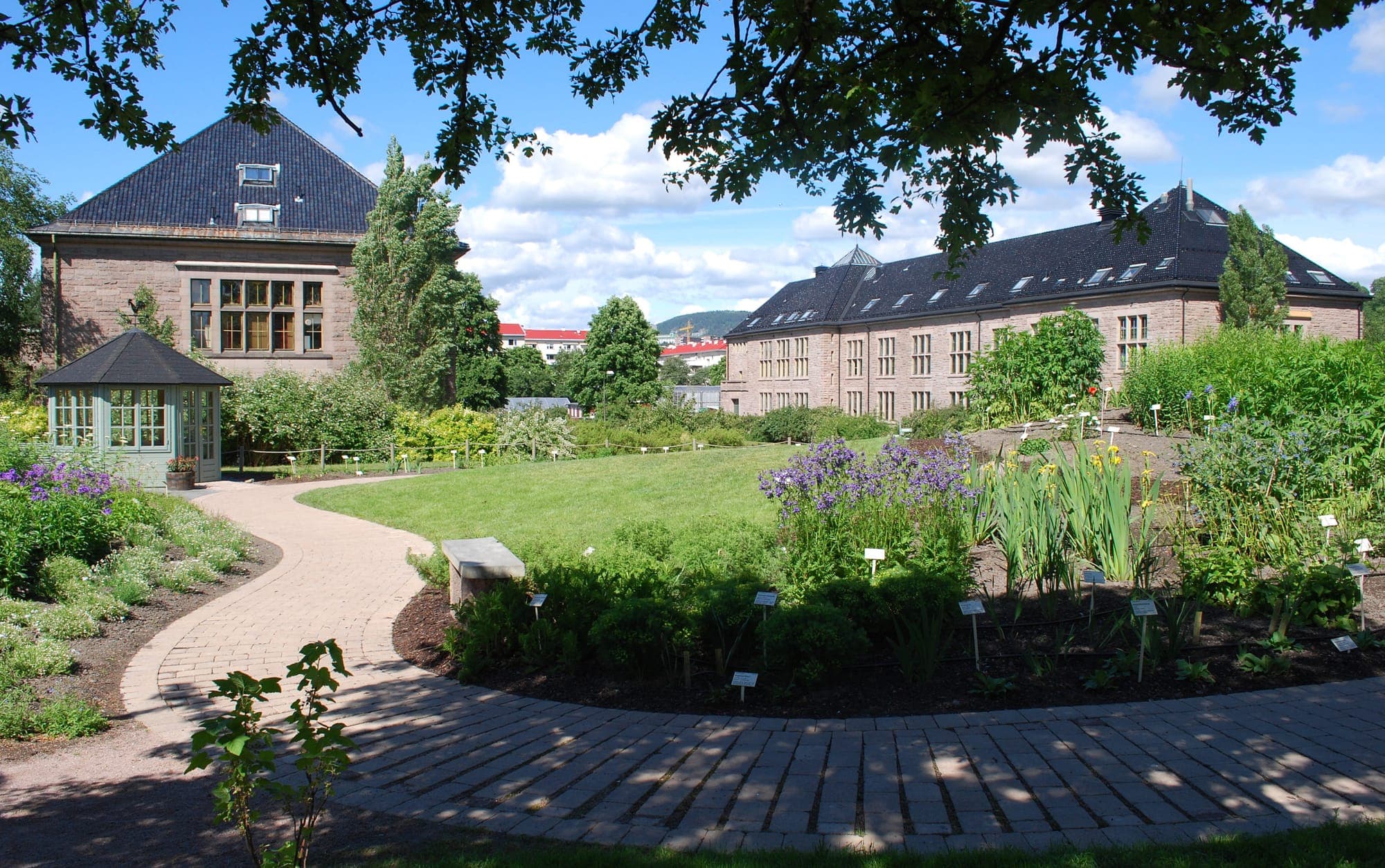 Path curving through flowerbeds toward the Botanical Garden's brick buildings