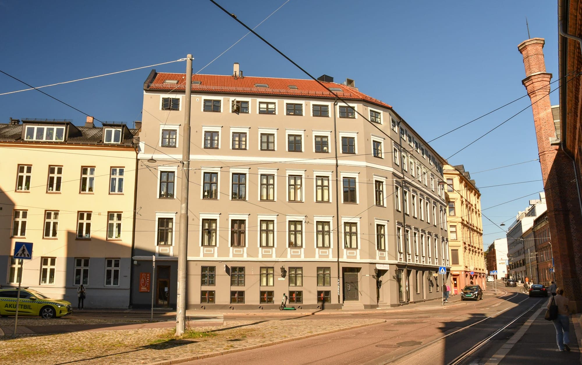 Grey corner block on a sunlit tram street in Frogner