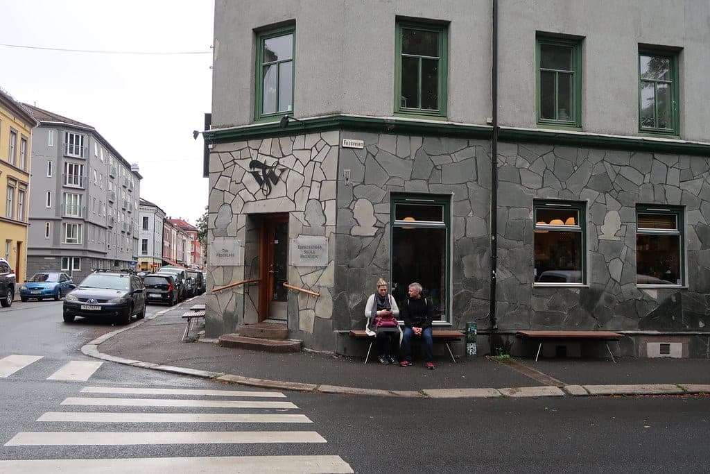The grey-stone corner storefront of Tim Wendelboe's coffee bar and roastery in Grünerløkka, Oslo, with green window frames and the TW logo.
