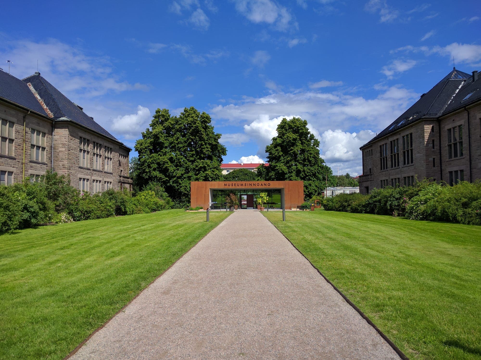 Straight gravel path between lawns to the museum garden's corten gate
